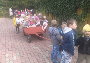 Dzieci ciągną wóz z koleżankami i kolegami.